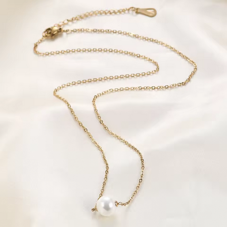 Collier La Perle de Foi de la marque MoonRose avec pendentif or et perle élégante, porté sur un modèle.