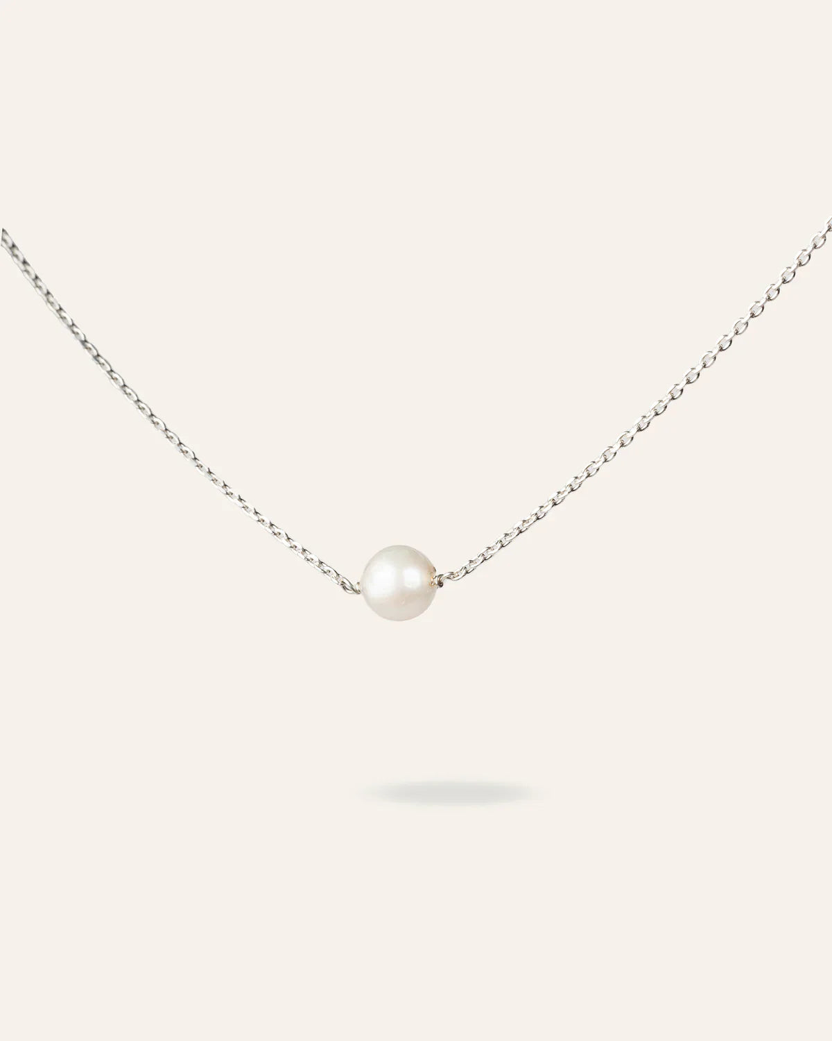 Collier La Perle de Foi de la marque MoonRose, chaîne en or avec une perle élégante, porté sur un fond neutre.